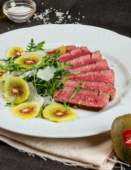 Tagliata di manzo con rucola, kiwi e petali di parmigiano