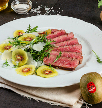 Carne bovina fatiada com rúcula, kiwi e pétalas de parmesão