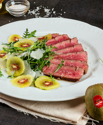 Gebratenes Rindfleisch mit Rucola, Kiwi und Parmesanblättern