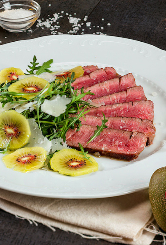 Carne bovina fatiada com rúcula, kiwi e pétalas de parmesão Carne bovina fatiada com rúcula, kiwi e pétalas de parmesão