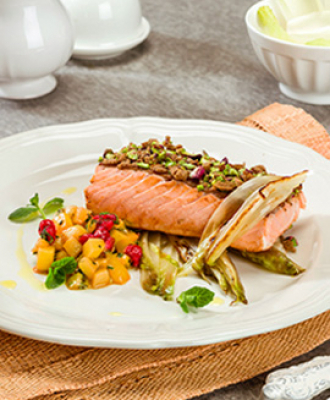 Lachs in Vollkornbrot-Pistazien-Kruste auf einem Bett aus gebratenem Chicorée mit würfelig geschnittener Kiwi, Johannisbeeren und Minze