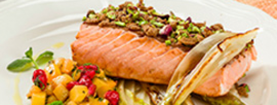 Salmón en costra de pan integral y pistachos sobre lecho de endivia belga salteada con dados de kiwi, grosella y menta